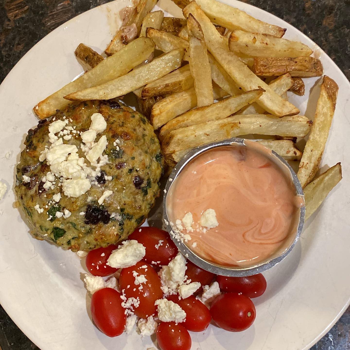 Greek turkey burger with oven fries, tomatoes, and feta