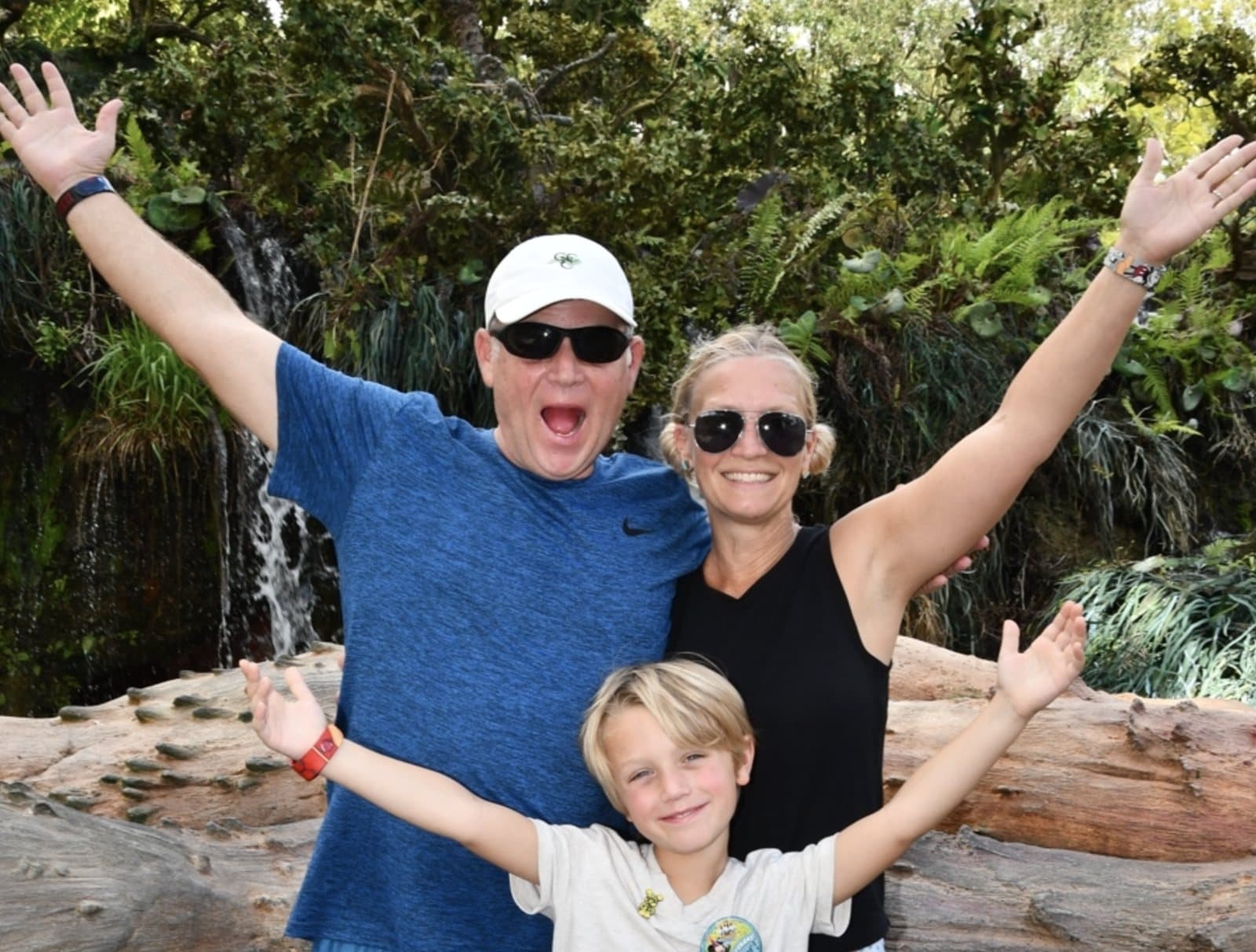 Kristin with her husband and son, arms raised and smiling