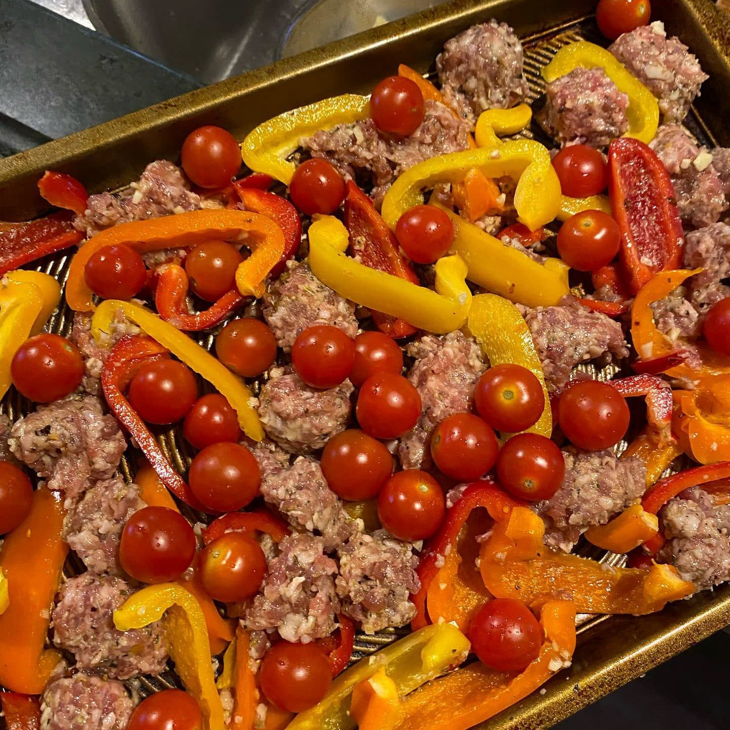 Sausage, cherry tomatoes, and peppers on a sheet pan