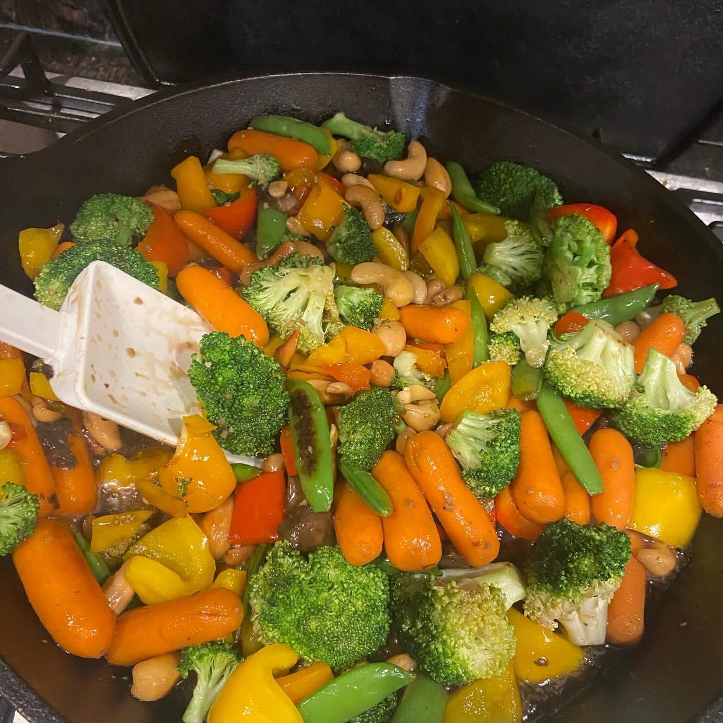 Broccoli, carrot, pepper, and cashew stir-fry in a cast iron skillet